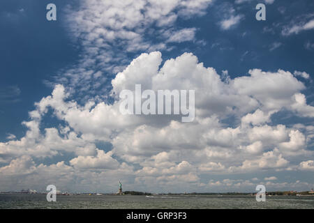 La vista del porto di La Statua della Libertà e l'alto cielo blu con nuvole sopra di esso. Foto Stock