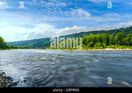 Bellissimo paesaggio fluviale con nuvoloso cielo blu riflessa nell'acqua limpida. Boscose rive di un lago di montagna. Estate idilliaco Foto Stock