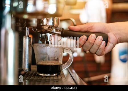 Cup e la macchina per espresso professionale versando il caffè fresco in una coppa in ceramica Foto Stock