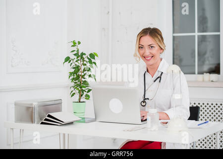 Ritratto di giovane donna medico con stetoscopio in camice bianco al computer Foto Stock