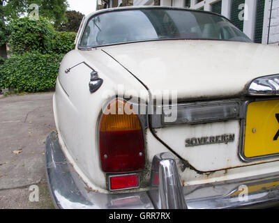 Un vecchio classico Jaguar auto cercando leggermente peggiore per usura su una città forcourt, Foto Stock