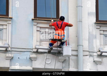 Builder lavoratore dipinto facciata di edificio alto con rolle Foto Stock