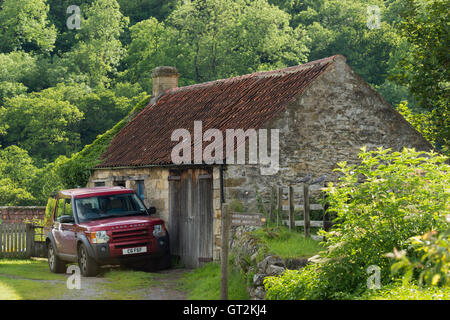 Sunny, vista serale di un Land Rover Discovery parcheggiato al di fuori di un fienile rustico nel grazioso villaggio di Rievaulx, North Yorkshire, Inghilterra. Foto Stock