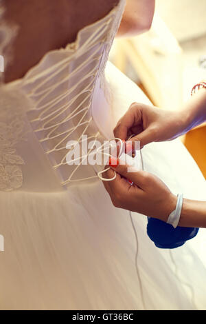 Closeup tonica foto di bella sposa di vincolare il suo abito da sposa Foto Stock