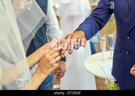 Sposa di mettere un anello di nozze su stallieri dito Foto Stock