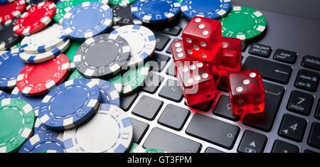 Casino chips, schede e dadi impilare su un computer portatile Foto Stock