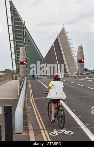 I ciclisti in bici sulla pista ciclabile di Twin vele il sollevamento ponte che attraversa il porto di Poole in Poole, Dorset nel mese di settembre Foto Stock