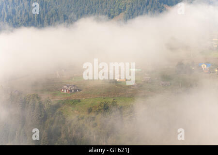 Fantastico scenario della campagna idilliaca con dolci colline velato di nebbia di mattina. Vista aerea di una collina Casale in una nebbiosa mattina di primavera Foto Stock