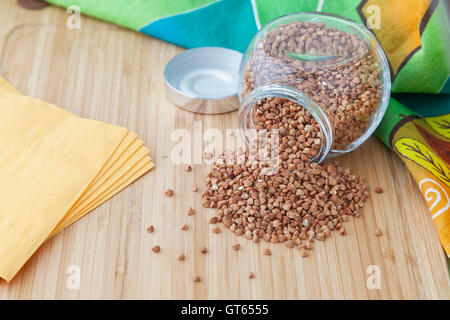 Chicchi di grano saraceno in un vasetto di vetro con tovaglioli su una tavola di legno Foto Stock