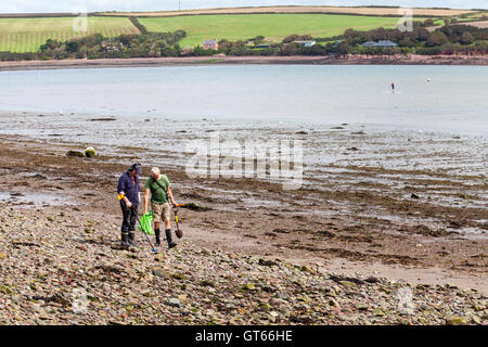 Due uomini usando un rivelatore di metalli a Dale beach, Pembrokeshire Foto Stock