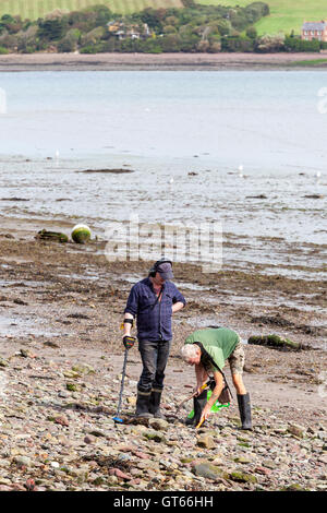 Due uomini usando un rivelatore di metalli a Dale beach, Pembrokeshire Foto Stock