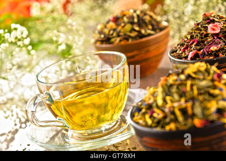 Composizione con tazza di tè e ciotole di foglie di tè. Foto Stock