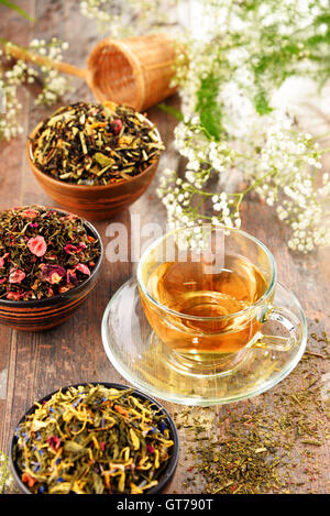 Composizione con tazza di tè e ciotole di foglie di tè. Foto Stock