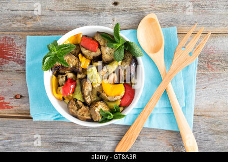 Vaso sano di succulenta turco di verdure alla griglia con melanzane, zucchine, rosso e giallo peperoni freschi e ciuffi di mi Foto Stock