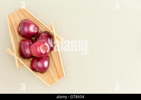 Sani e freschi Mele rosse su un vassoio in legno posto sulla sommità di un verde chiaro Tavolo, sottolineando la copia dello spazio. Catturate in un angolo alto V Foto Stock