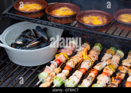 Deliziosi frutti di mare outdoor pasto presso il barbecue con il salmone grigliato shish kebab, marine cozze e vasi singoli di salsiccia stufata, Foto Stock