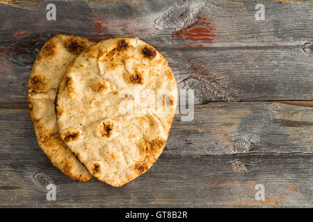 Semplicemente cotti al forno deliziosi crostini di grano intero pane naan focacce, un pane lievitato cotto in un tandoor forno di argilla, servita su autentici o Foto Stock