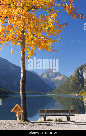 Panca e croce di legno di pioppo in autunno, Plansee, Tirolo, Austria Foto Stock