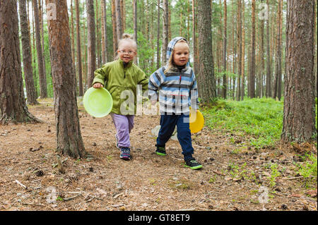 4 anno di età del fratello e sorella a piedi con i loro frisbees attraverso i boschi, Svezia Foto Stock