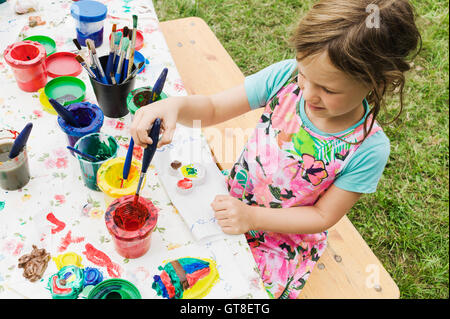 5 anno vecchia ragazza pittura presso un tavolo in giardino, Svezia Foto Stock