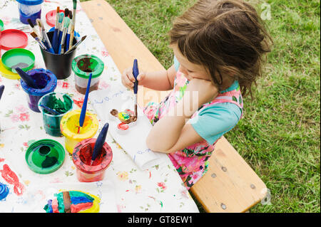 5 anno vecchia ragazza pittura presso un tavolo in giardino, Svezia Foto Stock