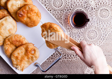 Donna che serve deliziosi piatti tradizionali Turchi pisi halka o pasta fritta con una tazza di tè turco, vista dal sovraccarico di sua mano Foto Stock