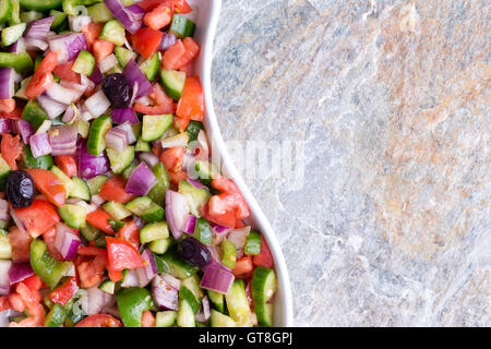 Colorato fresco pastore turco insalata servita in un moderno piatto ondulato su un sfondo di pietra con spazio copia a destra in un clo Foto Stock