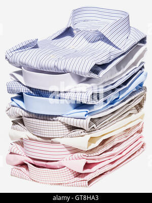 Pila di diverse camicie colorate su sfondo bianco Foto Stock