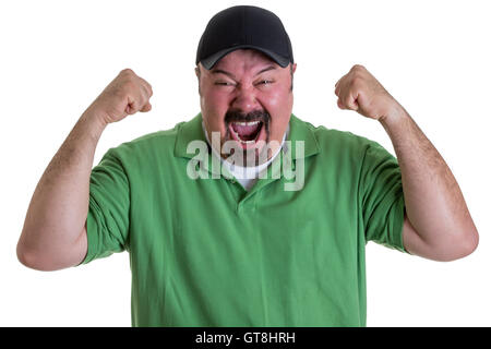 Vita di uomo eccitato con pizzetto indossando camicia verde e cappello da baseball tenendo i pugni in aria e di celebrare la vittoria di Team in Studio Foto Stock