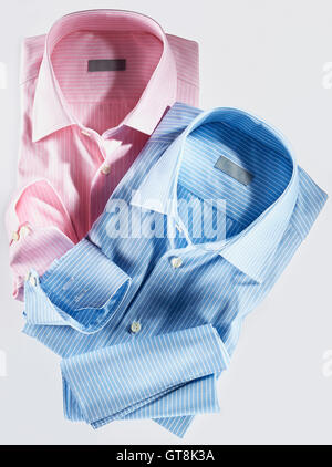 Due magliette, rosa e blu su sfondo bianco, studio shot Foto Stock