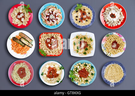 Vista dall'alto in basso su dodici square e piastre circolari riempiti con vari tipi di pasta conditi con scelta di carne e pesce, erbe, mar Foto Stock