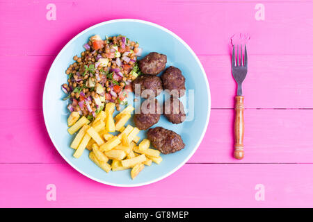 Piastra di fresco piccante artigianale tradizionale turca kofta polpette di carne serviti con una fresca insalata di lenticchie e patate fritte Patatine serviti Foto Stock