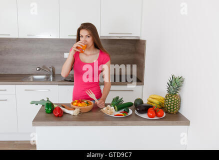 Con i capelli lunghi giovane donna si prepara un moderno ed elegante cucina sana insalata di verdure Foto Stock