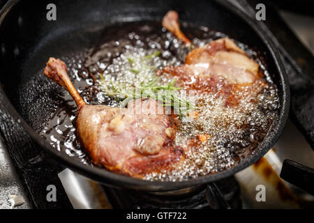 Gambe di anatra con rosmarino friggere in una padella Foto Stock