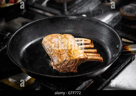 La cottura della cremagliera delle costolette di agnello su una cucina Foto Stock