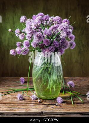 Bouquet di cipolla (erba cipollina) fiori in vaso sul tavolo di legno. Foto Stock
