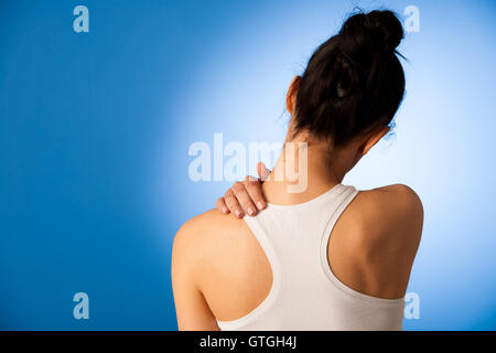 Donna con il dolore nel suo collo su sfondo blu Foto Stock