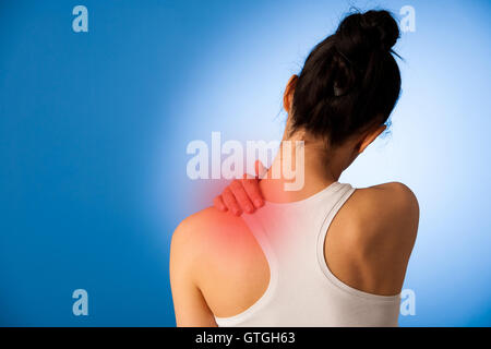 Donna con il dolore nel suo collo su sfondo blu Foto Stock