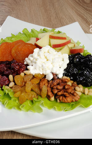 Vitamina insalata con dadi, mele, frutta secca e formaggio in foglie di lattuga Foto Stock