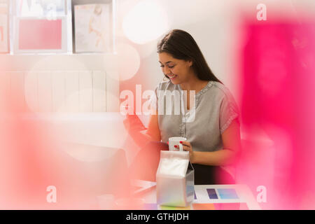 Sorridente acquirente di moda scrivere messaggi con il telefono cellulare e di bere il caffè Foto Stock
