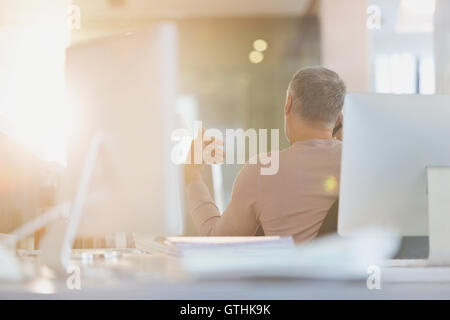 Imprenditore gesticolando alla scrivania in ufficio soleggiato Foto Stock