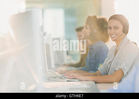 Ritratto sorridente imprenditrice con cuffia lavorando al computer in ufficio Foto Stock