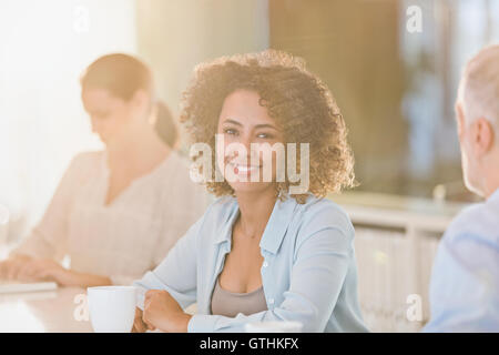 Ritratto sorridente imprenditrice di bere il caffè in riunione Foto Stock