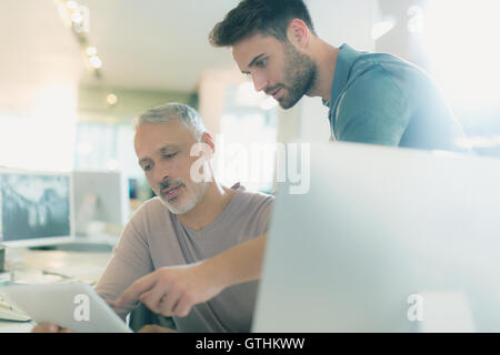 Imprenditori con tavoletta digitale parlando in ufficio Foto Stock