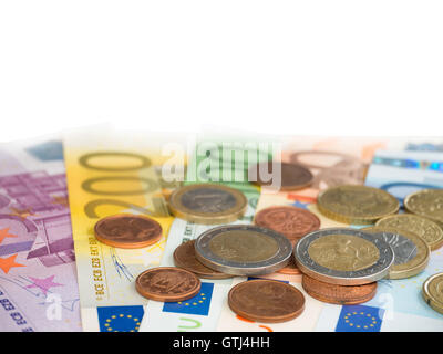 Colorate le banconote in euro di diversi valori e monete pila isolato su bianco Foto Stock