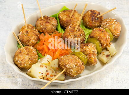 Le polpette di carne su bastoni in una piastra con verdure Foto Stock