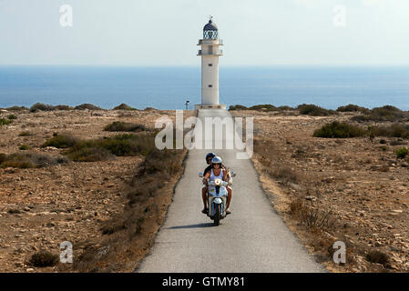 Due giovani motociclisti su una lunga strada di Es Cap de Barbaria faro, a Formentera, isole Baleari. Spagna. Barbaria cape fo Foto Stock