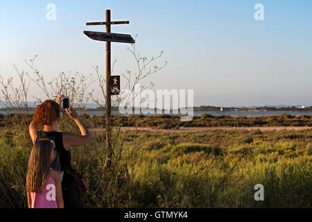 I turisti con bambini foto scattate al percorso ciclabile di segno. Pudent Lago. Formentera. Isole Baleari, Spagna, Europa. Foto Stock