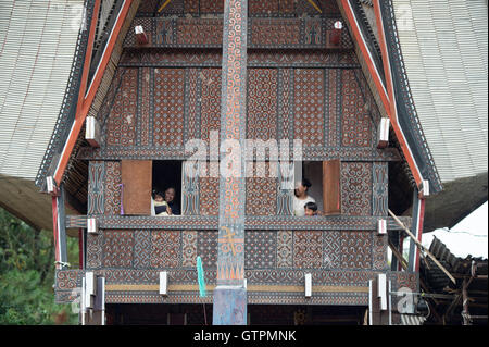 Toraja famiglia pongono per la telecamera nella finestra di Toraja casa tradizionale chiamato Tongkonan a Bagan Pangala village. Foto Stock