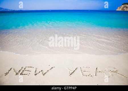 Felice Anno Nuovo scritto nella sabbia bianca Foto Stock